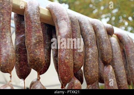 Würstchen. Würstchen hängen im Freien zum Verkauf auf einem Straßenmarkt. Hausgemachte Fleisch salami Wurst am Markt hängen in Zeile unter Sonnenlicht gut zu bilden Stockfoto