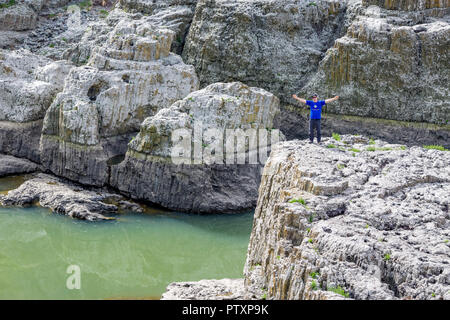 STUDEN KLADENETZ, Bulgarien - Mai 2, 2015: erwachsenen Mann im blauen T-Shirt und schwarzer Hut grüßt durch die Verbreitung von Waffen auf Felsen bei Devil Canyon natürliche Phänomen Stockfoto