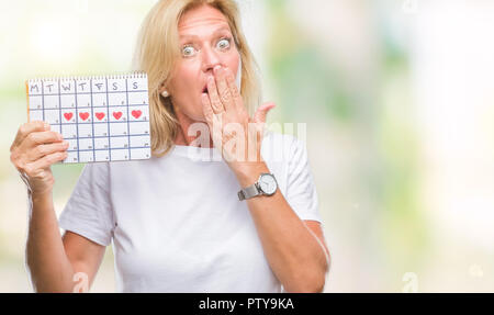 Mittleres Alter blonde Frau mit Menstruations Kalender ver isoliert Hintergrund decken den Mund mit der Hand mit Schande für den Fehler, den Ausdruck von Angst schockiert Stockfoto