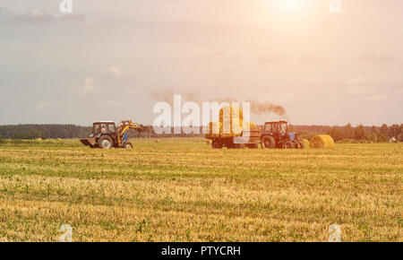 Landwirtschaft und Traktor sammelt Strohballen auf dem Bauernhof Anlage Stockfoto