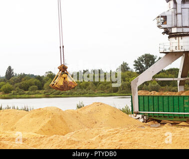 Port Lastkran Ladungen Holzhackschnitzel in Eisenbahnwaggons, Späne - Holz Stockfoto