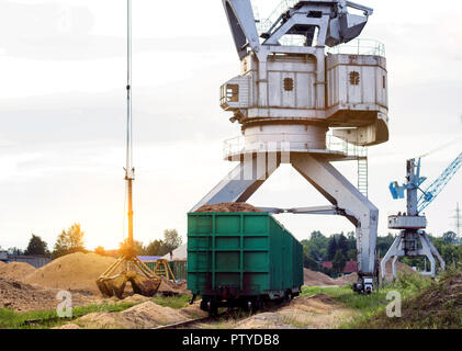 Der Hafenkran macht das Laden der Späne in die Güterwagen der Bahn, Laden, die Sonne Stockfoto