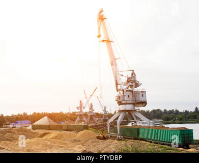 Der Hafenkran macht das Laden der Späne in die Güterwagen der Bahn, laden Stockfoto