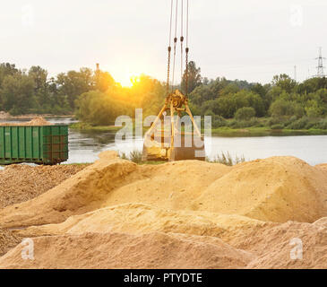 Der Hafenkran macht das Laden der Späne in die Waggons des Zuges, Nahaufnahme, Kelle Stockfoto