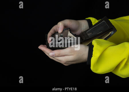 Mädchen gießen Münzen aus einem Geldbeutel, Nahaufnahme, schwarzer Hintergrund, Geld Stockfoto
