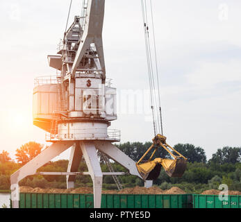 Port Lastkran Ladungen Holzhackschnitzel in Eisenbahnwaggons, Späne - Holz Stockfoto