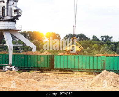 Port Lastkran Ladungen Holzhackschnitzel in Eisenbahnwaggons, Späne - Holz Stockfoto