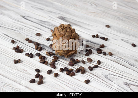 Pinienkerne und Pine Cone auf weißem Holz- Hintergrund Stockfoto