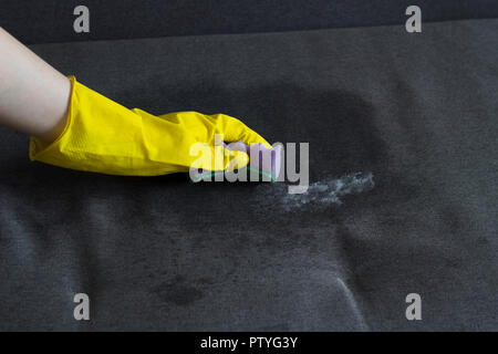 Mädchen in gelb Handschuhe reinigt das Sofa, close-up Stockfoto