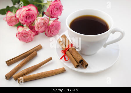 Eine Tasse Kaffee mit Zimt auf weißem Hintergrund. Rosen Stockfoto