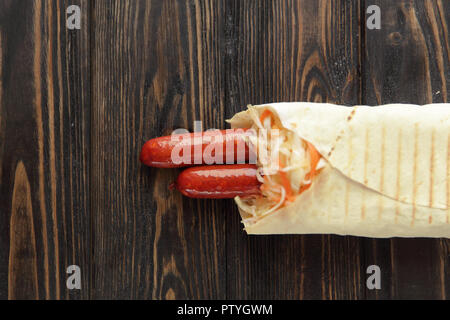 Ausschreibung Wurst in pita Brot auf hölzernen Hintergrund. Foto mit Co Stockfoto