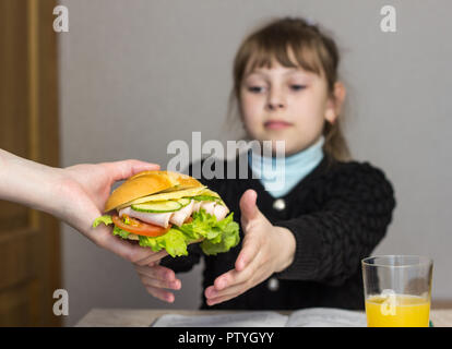 Mutter bereitet ein Sandwich für ein Kind in der Schule Stockfoto