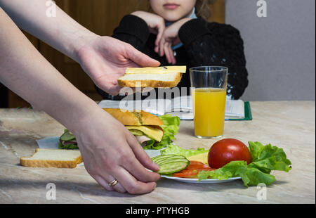 Mutter bereitet ein Sandwich für ein Kind in der Schule Stockfoto