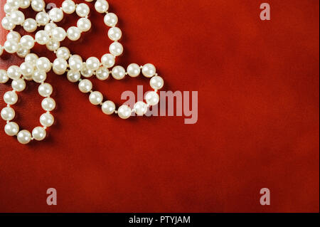 Weiße Perlenkette auf Rötlich braunem Leder Hintergrund. Stockfoto