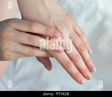 Ein Mädchen Schlieren eine Handcreme auf weißem Hintergrund Stockfoto