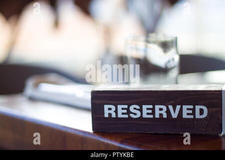 Holz- Karte Platte auf dem Tisch mit verschwommenen Hintergrund reserviert. Reservierung Sitz im Restaurant. - Freizeit, Menschen- und Servicekonzept. Stockfoto