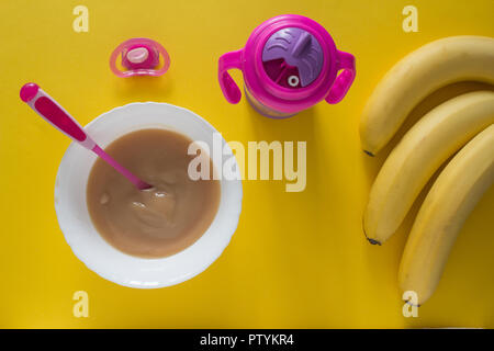 Baby Brei für Baby und Bananen auf gelbem Hintergrund Stockfoto