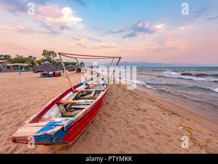 Burundi Bujumbura Lake Tanganyika, windiger bewölkter Himmel und Sand Strand am See in Ostafrika, Burundi Sonnenuntergang mit Boot aus Holz. Thatch afrikanischen Dach Stockfoto