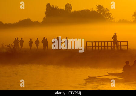 Ruderer und Läufer auf dem Fluss Cam in Cambridge bei Sonnenaufgang an den Start zu einem der wärmsten Oktober Tage für sieben Jahre. Die ruderer waren zu einem goldenen Sonnenaufgang heute morgen behandelt (Tue), wie sie früher auf dem Fluss Cam am Beginn der heißesten Oktober Tag in sieben Jahren ausgebildet. Die Sonne stieg in den nebeligen Wasser im Herzen der Universitätsstadt im südlichen England wird erwartet, einen warmen und sonnigen Tag mit Höhen von 24 C zu genießen Stockfoto