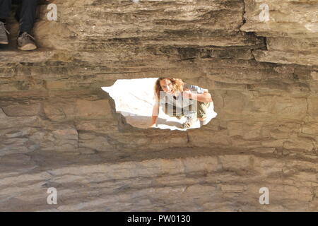 Junger Mann mit langen, lockigen Haar Lächeln durch Höhle öffnen Stockfoto