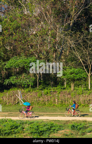 Vang Vieng, Laos - Januar 19, 2017: Unbekannter Mädchen Radfahren auf einer Landstraße in Vang Vieng Dorf, Laos. Stockfoto