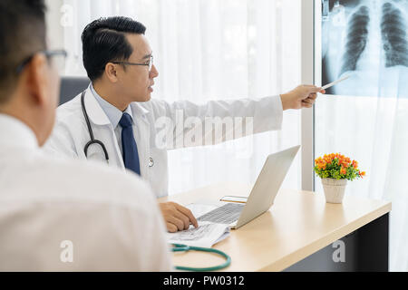 Professionelle Arzt erklären über x-ray Ergebnis zu Patienten in der Arztpraxis Krankenhaus Stockfoto