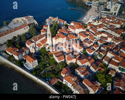 Majestic sonnigen Stadtbild der Altstadt von Budva in Montenegro. Es ist Saint Ivan und Heilige Dreifaltigkeit Kirchen, alte Häuser mit roten Dächern, Geschindelten - orange Stockfoto