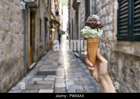 Woman's Hand hält das Eis in der Waffel Kegel auf dem Hintergrund der sonnigen alten Straße in Dubrovnik in Kroatien. Horizontale Foto. Stockfoto