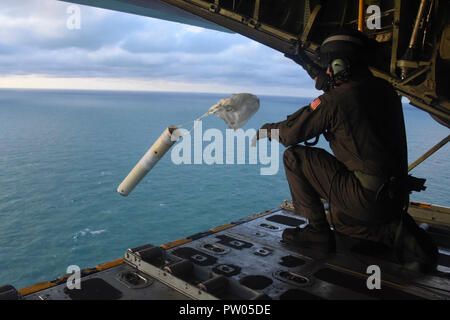 Der Küstenwache Besatzungsmitglied an Bord eines HC-130 Hercules Flugzeug von Air Station Clearwater, Florida, fällt einem Selbst - Suche Datum marker Boje die Sturmflut während einer Antenne Bewertung der Schäden durch den Hurrikan Michael in der Nähe von Apalachicola, Florida, Donnerstag, Oktober 11, 2018 zu bestimmen. (U.S. Coast Guard Foto von Petty Officer 2. Klasse Ashley Johnson). Stockfoto