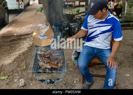 LUANG PRABANG, LAOS - OKTOBER 4: unbekannter Mann gegrilltes Fleisch auf der Seite der Straße am 4. Oktober in Luang Prabang, Laos 2017. Stockfoto