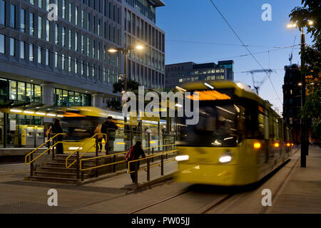 Zwei Metrolink Tram verlassen St. Peter's Square Stop in der Nacht im Stadtzentrum von Manchester, UK. Stockfoto