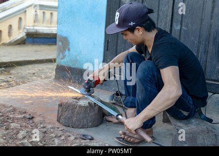 LUANG PRABANG, LAOS - OKTOBER 8: Ein unbekannter Mann schleift ein traditionelles Laos Schwert in einem lokalen Dorf in Luang Prabang, Laos am 8. Oktober, 201 Forge Stockfoto