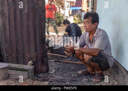 LUANG PRABANG, LAOS - OKTOBER 8: Ein unbekannter Mann prüft ein Messer nach dem Brennen der Tang in den Griff zu einem Dorf in Luang Prabang, Laos Forge Stockfoto