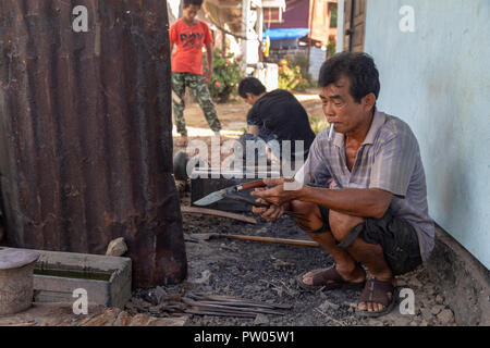 LUANG PRABANG, LAOS - OKTOBER 8: Ein unbekannter Mann sieht einen rauchen Messer in einem lokalen Dorf in Luang Prabang, Laos am 8. Oktober 2017 zu schmieden. Stockfoto