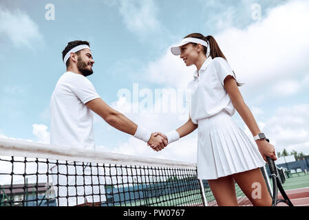 Das Händeschütteln nach dem guten Spiel. Der Mann und die Frau in der Armband schütteln Hände auf Tennis net Stockfoto