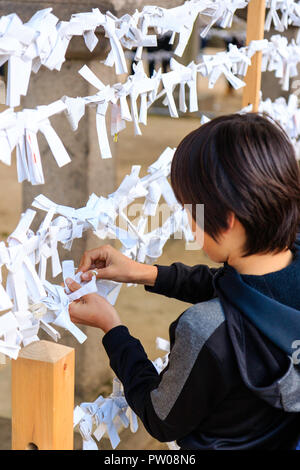 Japanische neues Jahr, shogatsu. Junge Junge, 9-10 Jahre alt, Binden schlechtes Vermögen Papierstreifen, Omikuji zu arbeiten Rahmen Pech hinter sich zu lassen. Nishinomiya Shri Stockfoto