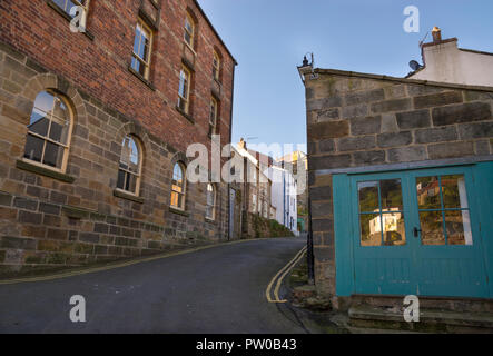 Schmale Gasse hinunter zum Fluss im historischen Dorf Staithes an der Küste von North Yorkshire, England. Stockfoto