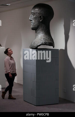 Ein Besucher schaut auf eine Hommage Kopf auf Anzeige an der Elisabeth Frink Menschen und andere Tiere Ausstellung Vorschau am Sainsbury Zentrum für Bildende Kunst in Norwich, Norfolk. Stockfoto