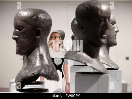 Ein Besucher schaut den Tribut Köpfe auf der Elisabeth Frink Menschen und andere Tiere Ausstellung Vorschau am Sainsbury Zentrum für Bildende Kunst in Norwich, Norfolk. Stockfoto