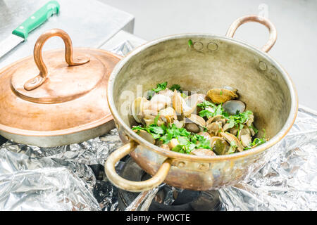 Teil der Muscheln mit Lorbeerblättern und Knoblauch in einem Topf auf Gas Herd Stockfoto