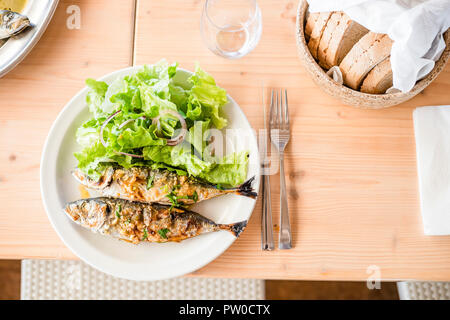 Zwei frisch gegrillte Sardinen mit Salat Salat und Brot serviert. Stockfoto