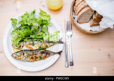 Zwei frisch gegrillte Sardinen mit Salat Salat und Brot serviert. Stockfoto