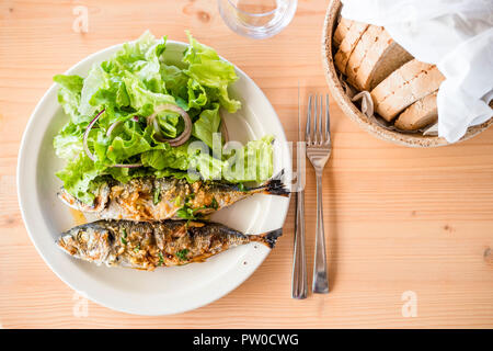 Zwei frisch gegrillte Sardinen mit Salat Salat und Brot serviert. Stockfoto