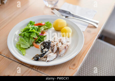 Frisch gegrillte goldener Fisch mit gekochten Kartoffeln und Salat im Restaurant Stockfoto