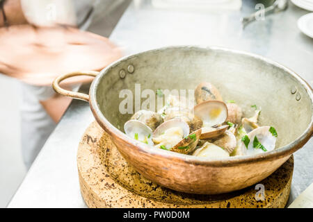 Teil der Muscheln gebraten mit Knoblauch und Koriander in einem kupfernen Topf im Restaurant Stockfoto