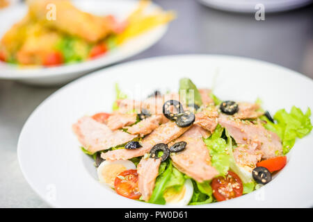 Lecker Thunfisch Salat mit schwarzen Oliven auf weiße Platte serviert. Stockfoto