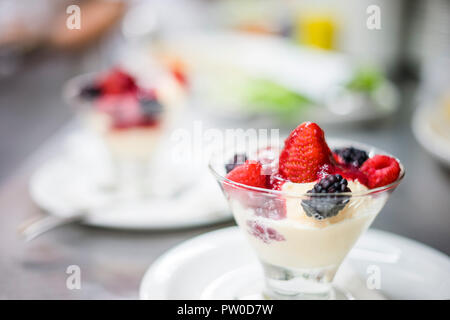 Glas Schüssel voll mit Vanille Eis, Obst und Marmelade Stockfoto