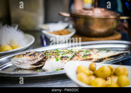 Frisch gegrillte goldenen Fisch auf silbernem Tablett mit gebackenen Kartoffeln im Restaurant Stockfoto