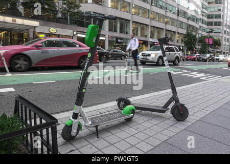 Überspringen Scooter Fahrer in bikelane, 2 dockless Elektroroller geparkt, Downtown, DC. Kalk - S&Vogel dockless Roller Scooter Unternehmen, die in DC Stockfoto