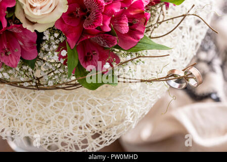 Schließen bis auf ein paar Ringe auf Zweig der Blumenstrauß mit rosa Blüten und Blätter auf Spitze Deckchen. Stockfoto